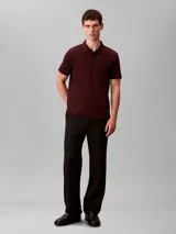 Chomba de manga corta Calvin Klein confeccionada en algodón interlock, con cuello clásico y cierre frontal de botones. Presenta un diseño liso en color bordó con el logo de la marca bordado discretamente en el pecho.