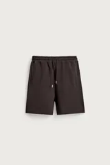 Bermuda tipo jogger de ajuste relajado, color marrón oscuro, confeccionada en tejido interlock de algodón con elasticidad. Presenta cintura elástica ajustable con cordón y bolsillos laterales de vivo.