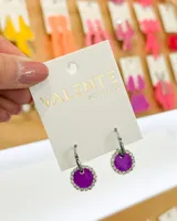 Aros colgantes con aro de acero plateado y dije circular color violeta con borde de strass.