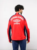 Buzo de entrenamiento Umbro del Club Nacional de Football, con cierre frontal parcial y cuello alto. Presenta un diseño con bloques de color azul, blanco y rojo, con panel frontal acolchado y mangas largas con aberturas para pulgares.