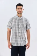 Camisa de manga corta confeccionada en mezcla de lino y algodón, con diseño a cuadros en tonos gris, blanco y azul. Presenta cuello camisero con botones y bolsillo ojal en el pecho con detalle bordado.