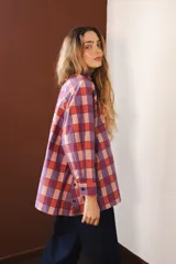 Camisa de manga larga con cuello clásico y cierre frontal de botones. Presenta un diseño de rayas verticales verdes y blancas con un estampado lineal de pequeñas flores rojas.
