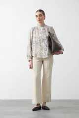 Pantalón de corte recto y tiro alto, color beige, con costuras verticales frontales y bolsillos laterales. Presenta una estructura de sarga resistente y cierre frontal.