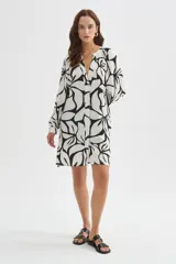 Camisa tipo vestido de viscosa con estampado floral abstracto en blanco y negro, cuello en V con botonera frontal completa, mangas largas abullonadas y diseño holgado.
