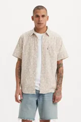 Camisa de manga corta con estampado floral, cuello clásico, cierre frontal con botones y un bolsillo en el pecho con etiqueta roja distintiva de la marca.