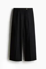 Pantalón sastrero de tiro alto y pierna ancha, confeccionado en una mezcla liviana de lino y viscosa. Presenta un diseño tobillero con cierre frontal, pretina con botón, pliegues marcados en la parte delantera y trasera, bolsillos laterales al bies y bolsillos decorativos en la parte posterior.