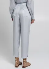 Pantalón cropped de tiro alto con cintura elástica ajustable mediante lazo. El tejido es ligero y presenta un acabado ligeramente satinado, en un tono celeste o gris muy claro.