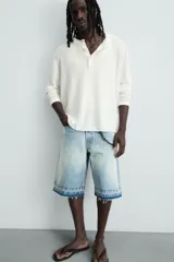 Bermuda de denim de algodón, color negro lavado, de corte ancho (baggy fit) y tiro medio. Presenta cinco bolsillos y bajo con acabado irregular deshilachado.