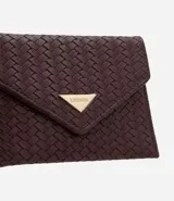 Billetera pequeña tipo sobre con textura trenzada tressê, confeccionada en cuero sintético. Presenta un cierre con botón a presión y un aplique metálico triangular decorativo en la solapa.
