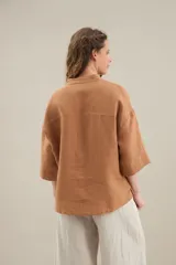 Camisa de lino de calce relajado, color negro, con cuello mao, mangas cortas y bajo redondeado con aberturas laterales.