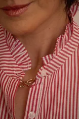 Camisa de corte clásico con estampado de rayas verticales rojas y blancas, cuello camisero con volados y cierre frontal de botones.