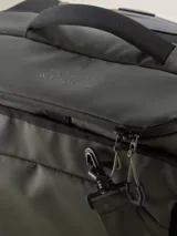 Valija gris con ruedas, manija extensible y múltiples bolsillos con cierre.