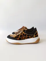 Championes deportivos de cuero con estampado animal print, cordones marrones y suela blanca con base color caramelo.