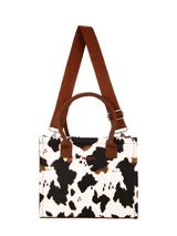 Cartera Terrano modelo Moon de diseño estructurado, con estampado animal print tipo vaca en tonos blanco, negro y marrón. Cuenta con manijas cortas de mano marrones, correa larga ajustable marrón con logo grabado y herrajes metálicos plateados.