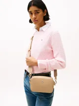 Bandolera Tommy Hilfiger color beige con monograma TH en relieve, cierre de cremallera, correa de cadena dorada extraíble y ajustable, bolsillo interior con cremallera, monedero extraíble con cremallera y logo TH dorado en el frente.