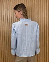 Blusa blanca de algodón con escote en V y cuello mao. Presenta mangas largas abullonadas con puños acampanados y fruncidos.