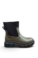 Bota corta de cuero color verde militar con caña elástica en tejido tipo canalé de color negro. Cuenta con suela track gruesa de goma negra.