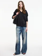 Sweater negro de hilo con textura brillosa, escote en V y manga larga.