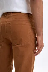Pantalon de corte recto confeccionado en pana color tostado, con diseño clásico de cinco bolsillos y cierre frontal con botón y cremallera.