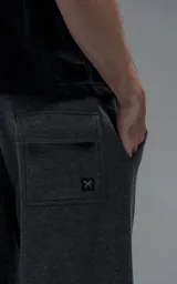 Pantalón tipo jogger gris melange de corte baggy y silueta amplia, confeccionado en frisa de algodón. Presenta cintura elástica, bolsillos laterales de mano y bolsillos estilo cargo con solapa y cierre en los laterales.