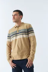 Remera tipo polo de manga larga azul marino con rayas horizontales blancas, grises y rosadas en el pecho. Tiene cuello clásico con botones y logo estampado en el pecho. Corte regular.