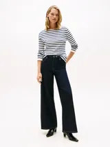 Remera de manga larga con cuello barco y diseño de rayas horizontales en azul marino y blanco. Presenta un pequeño logo bordado en el pecho y puños con detalle de volado.