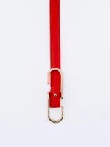 Cinto fino de cuero rojo con hebilla dorada en forma de U.