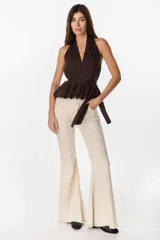Blusa de cuello halter en color beige, con escote en V pronunciado, corte ajustado en el torso y detalle de volados fruncidos en la cintura con un lazo lateral ajustable.