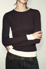 Camiseta de manga larga color gris melange, con cuello redondo y bajo recto. Presenta un detalle de tejido efecto doble a contraste en el cuello, puños y dobladillo inferior en color blanco.