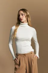 Polera de tejido fino color negro, con cuello alto y mangas largas con terminación sutilmente fruncida. Diseño ajustado al cuerpo.
