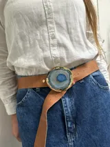 Cinturón de cuero marrón con hebilla circular de bronce que presenta una piedra ágata natural en tonos turquesa y azul engarzada en el centro.
