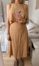 Conjunto de dos piezas compuesto por un top corto sin mangas y una pollera larga con tajo lateral. El top presenta un diseño minimalista y la pollera es ajustable en la cintura.