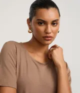 Mono de mujer color marrón topo, con escote redondo, mangas cortas y pantalón ancho. Incluye un cinturón ancho del mismo tejido que se anuda con una hebilla metálica redonda.