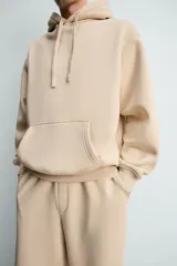 Sudadera con capucha de corte relajado, confeccionada en tejido de algodón con interior perchado. Presenta mangas largas, bolsillo frontal tipo canguro y terminaciones en rib.