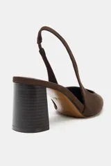 Zapato destalonado de gamuza color marrón con tacón en bloque de altura media y punta fina. Presenta una tira trasera con elástico para mayor ajuste.