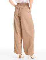 Pantalón tipo palazzo de corte ancho y fluido, confeccionado en tejido sastrero. Presenta tiro alto con doble abotonadura frontal, pinzas decorativas y cintura elástica en la parte posterior. Incluye bolsillos laterales funcionales.