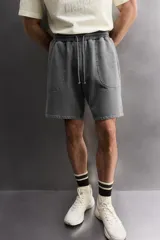 Short tipo jogger de algodón con interior afelpado, cintura elástica ajustable con cordón, bolsillos frontales y bolsillo trasero. Presenta un efecto lavado y estampado gráfico a contraste en el frente.