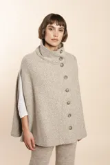 Capa color beige con textura de espiga, cuello alto con botones y aberturas laterales para los brazos. Confeccionada en lana fina sin teñir.