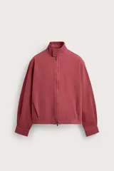 Cazadora relaxed fit de algodón lavado color bordó, con cuello subido y cierre frontal de cremallera de doble dirección. Cuenta con bolsillos ocultos en las costuras de la cadera y mangas largas con puños abotonados.