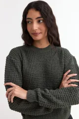 Sweater de punto con textura tipo waffle, color blanco, de corte clásico con cuello redondo y mangas largas.