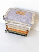 Billetera grande de cuero con cierre metálico perimetral. Presenta un diseño rectangular con textura tipo reptil, monedero interno y espacio para billetes extendidos.