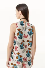 Top sin mangas con cuello a la base, estampado con flores naranjas y pájaros rojos.