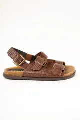 Sandalias de cuero color marrón con textura trenzada, plantilla anatómica de corcho y suela dentada. Posee tres tiras ajustables con hebillas metálicas y tira en el talón.
