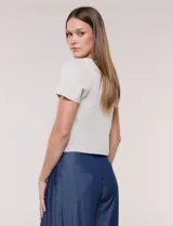 Cardigan corto de tejido de punto fino con hilo brillante de lurex y destellos metalizados. Presenta escote en V pronunciado, mangas cortas, cierre frontal con botones a tono y ruedo con terminación en pico en el frente.