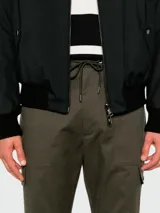 Pantalón cargo deportivo color verde oscuro, con cintura elástica ajustable con cordón, bolsillos laterales con solapa y bolsillos traseros con cierre de botón a presión. Corte recto y tobillos con puños elásticos.