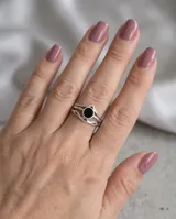 Anillo de acero con piedra central de ónix negro y diseño de bandas entrelazadas.