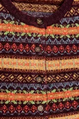 Chaqueta corta de punto con diseño jacquard multicolor, cuello redondo, manga larga y cierre frontal con botones.