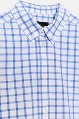 Camisa de manga larga con cuello solapa y cierre frontal de botones. Tejido de popelín 100% algodón con estampado a cuadros azules y blancos. Bajo con corte evasé.