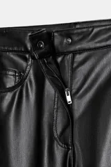 Pantalón de tiro medio confeccionado en tejido efecto piel. Presenta un diseño de pierna ancha tipo balloon, cintura con trabillas, cierre frontal con cremallera y botón, y cinco bolsillos.