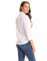 Camisa blanca de algodón con cuello clásico, cierre frontal con botones nacarados, mangas tres cuartos con puños anchos rebatibles y corte entallado con pinzas.